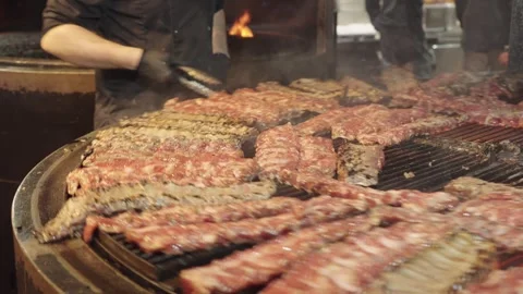 Cook Turning Pork Ribs While Grilling Them on a Rotisserie Video stock 345521898