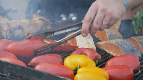 Cook turns grilled vegetables. Salmon meat, red fish and fried pepper, barbecue Stock Footage 118461453