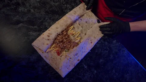 The cook twists the pita bread into a bundle, making shawarma 库存影片 172494724