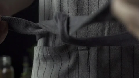 Cook is tying a gray kitchen apron, cooking in slow motion Stock Footage 96858805