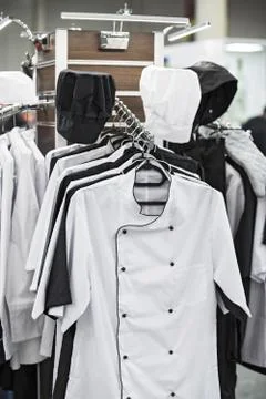 Cook uniform in a restaurant on a hanger, white and black uniforms, shirts an Stock Photos