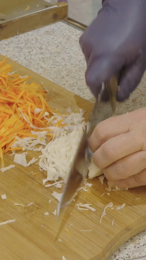 The cook uses a kitchen knife to cut white cabbage and carrots Stock Footage 270899304