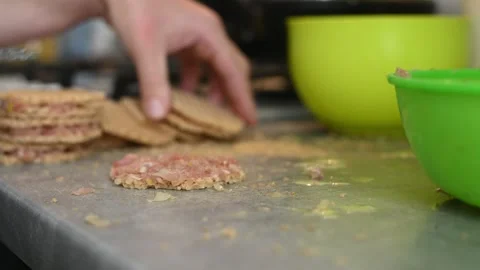 Cook uses metal fork to spread raw minced meat on round waffle sheet. Stock Footage 342266409