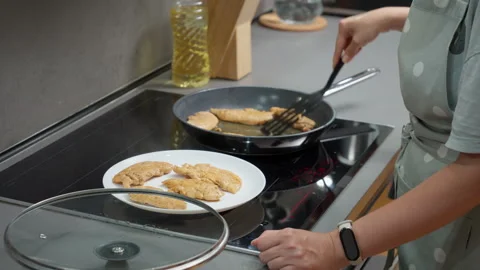 A cook uses a spatula to put fried chicken from a hot pan onto a plate Stock Footage 315509155