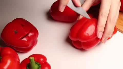 A cook is using a knife to slice a red bell pepper. Stock Footage 281828296