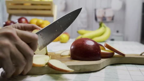 Cook using sharp knife to cut apple into smaller slices on cutting board in Stock Footage 341206471