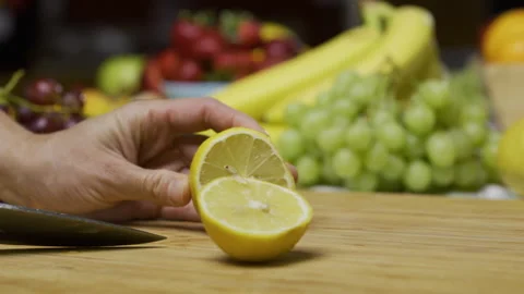 Cook using sharp knife to slice through juicy lemon on cutting board - closeup Stock Footage 341226252