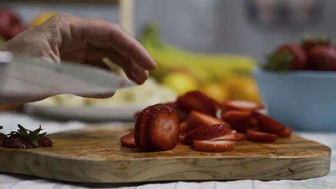 Cook using small knife to slice up strawberries on cutting board in kitchen, Stock Footage 341232080