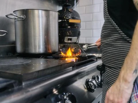 Cook using tongs to remove charcoal that is on the fire in a restaurant Stock Photos