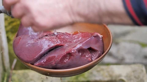 The cook washes the beef liver under the tap in the yard Stock Footage 125698012