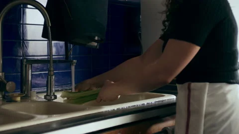 Cook washing celery in a large kitchen with an array of a equipment and applianc Stock Footage 199462825