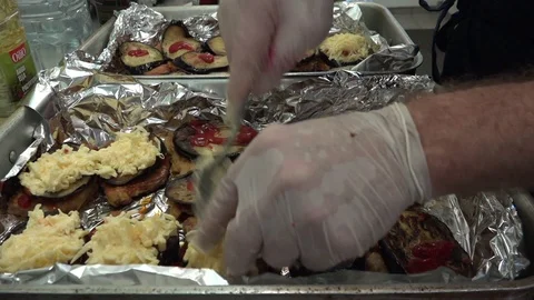 Cook in white gloves puts grated cheese on aubergine slices Stock Footage 118357121