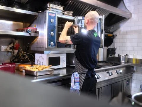 Cook working in a restaurant kitchen preparing the oven Stock Photos