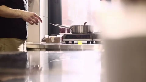 The cook works with an induction hob. The process of frying or stewing close-up. Stock Footage 233296849
