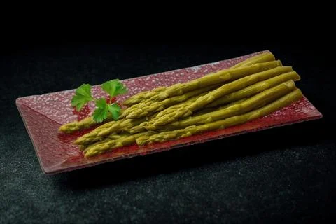 Cooked asparagus spears on a decorative rectangular plate Stock Photos