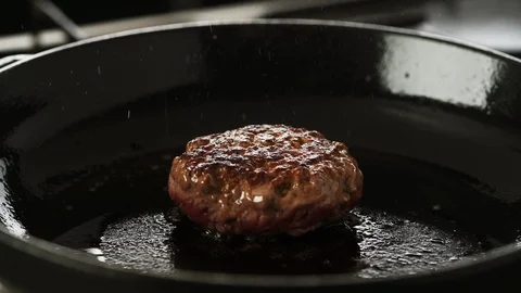 Cooked Beef patty gently cooking in a hot cast iron pan Stock Footage 92149838