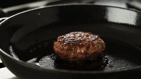 Cooked Beef patty gently cooking in a hot cast iron pan Stock Footage 92150940