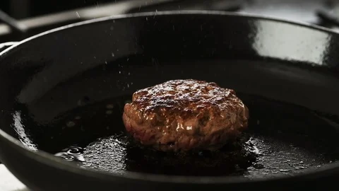 Cooked Beef patty gently cooking in a hot cast iron pan Stock Footage 92151087