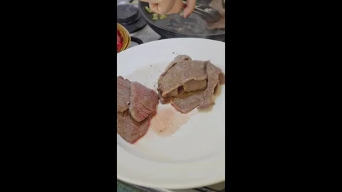 Cooked beef slices being transferred onto plate close up Stock Footage 331196425