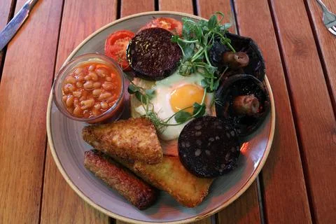 Cooked breakfast with fried eggs, hash browns, baked beans, black pudding Stock Photos