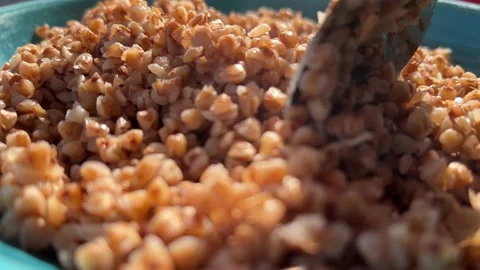 Cooked buckwheat stirring with a spoon on the blue dish. Stock Footage 204146432