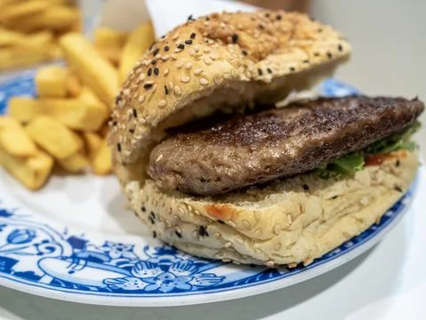 Cooked burger patty in a bread bun with black and white sesame seeds Stock Photos