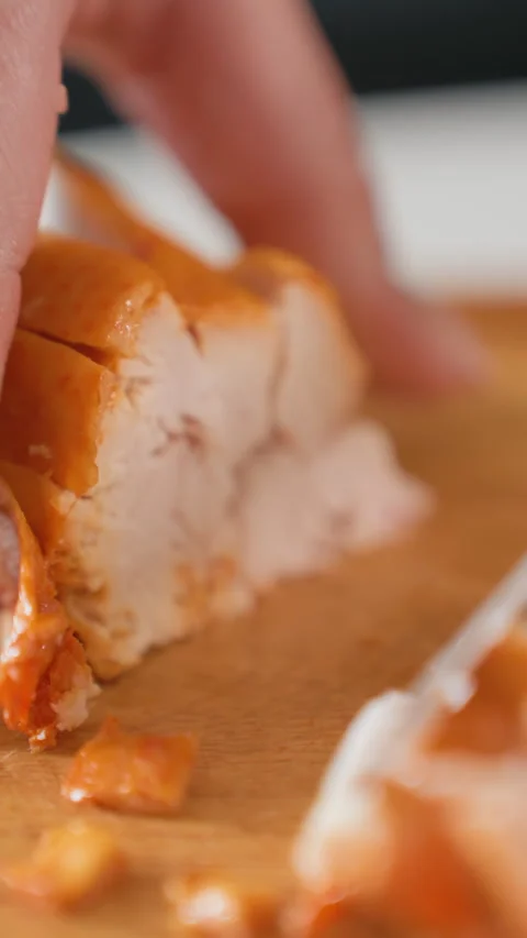 Cooked chicken breast being sliced on wooden cutting board with fingertip Stock Footage 343679768
