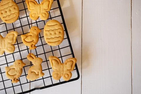 Cooked cookies in the form of Easter symbols cool down on a metal grate for b Stock Photos