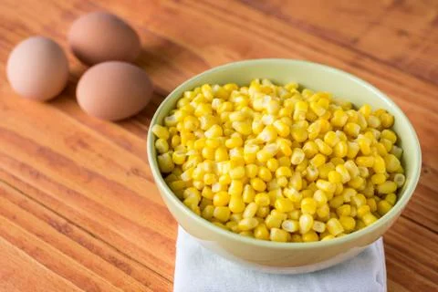 Cooked corn in the bowl on the table with boiled eggs in the background Stock Photos