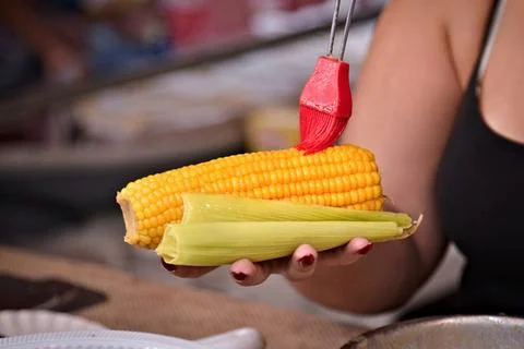 Cooked corn on the cob being held by an unrecognizable woman's hand Stock Photos