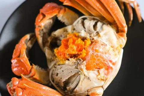 Cooked crab with orange roe on black plate Stock Photos