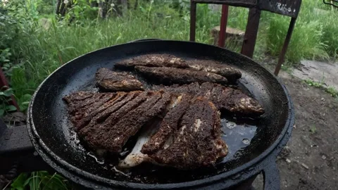 Cooked fish frying in a large cast-iron pan outdoors. Stock Footage 310705746