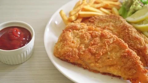 Cooked fish steak with lemon and sauce on white plate Stock Photos
