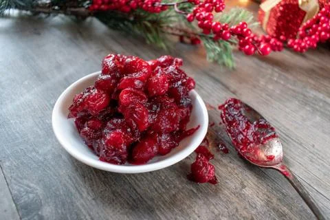 Cooked fresh red cranberries on white dish in festive Christmas setting Stock Photos