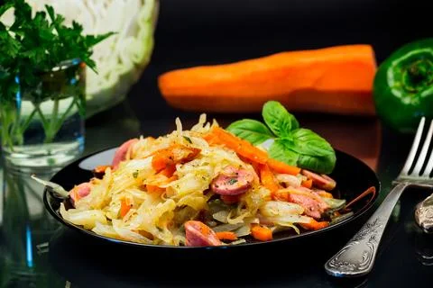 Cooked fried cabbage with vegetables and sausages Stock Photos