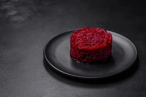 Cooked grated beetroot formed as a cylinder and ready dish on a black plate Stock Photos