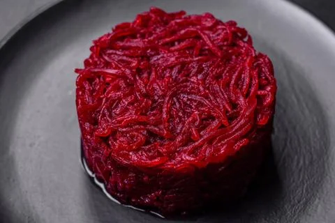 Cooked grated beetroot formed as a cylinder and ready dish on a black plate Stock Photos