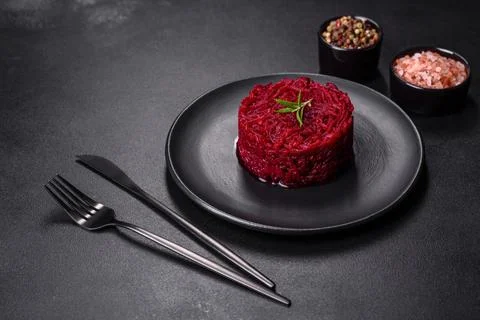 Cooked grated beetroot formed as a cylinder and ready dish on a black plate Foto stock