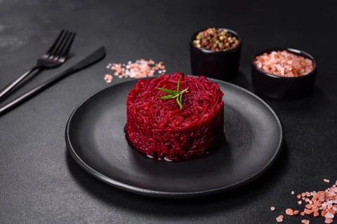 Cooked grated beetroot formed as a cylinder and ready dish on a black plate Stock Photos