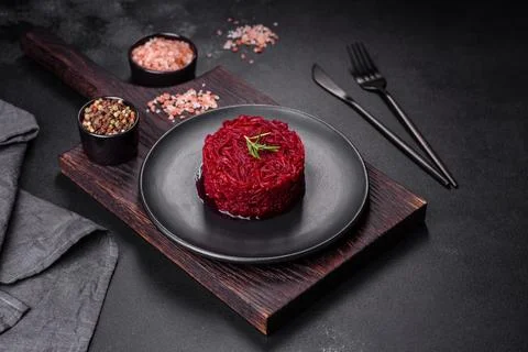 Cooked grated beetroot formed as a cylinder and ready dish on a black plate Stock Photos