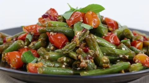 Cooked green beans, red cherry tomato with sesame seeds in black plate Stock Footage 75005076