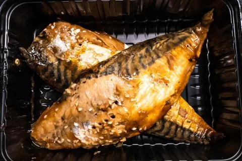 Cooked headless mackerel in a black plastic container Foto stock