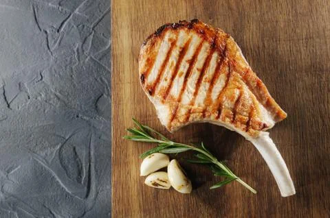 Cooked hot steak on the bone with baking and garlic on a wooden board view from Stock Photos