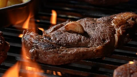 Cooked juicy steak meat beef with garlic and seasoning on top on a flaming grill Stock Footage 170318134