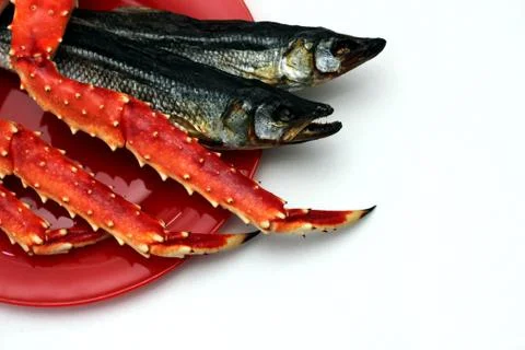 Cooked Kamchatka crab and dried salted fish on a red plate. Beer snack. Stock Photos