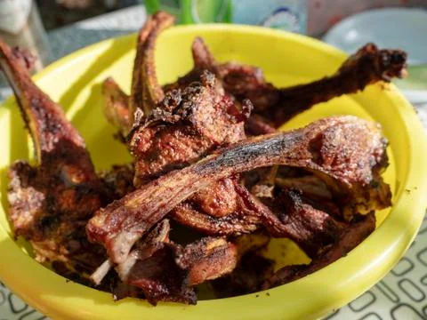 Cooked lamb ribs on the grid are in a yellow bowl on the table Stock Photos