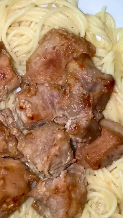 Cooked meat chunks served over white spaghetti pasta noodles Stock Footage 331974781