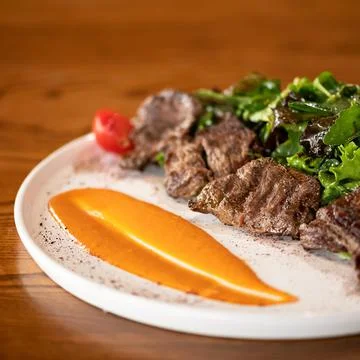 Cooked meat with mashed corn puree and salad garnish. White plate of food on Stock Photos
