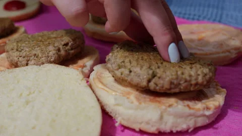Cooked Meat Patties Assembled on Sauce Spread Burger Buns on Pink Surface Stock Footage 341998438