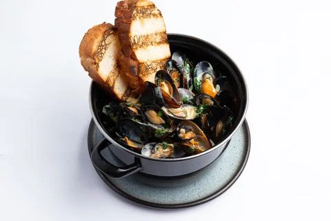 Cooked mussels and fried bread in a pan. Stock Photos